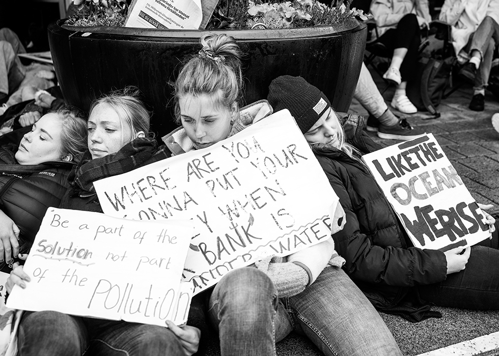 Ett gäng demonstranter sitter på gatan