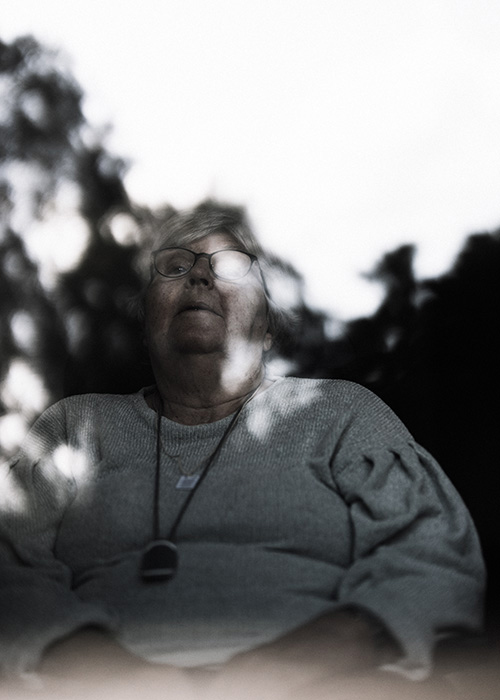 En äldre kvinna fotograferad genom ett fönster