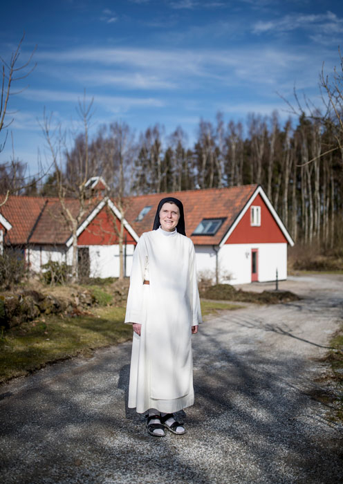 En nunna står utomhus vid ett äldre hus