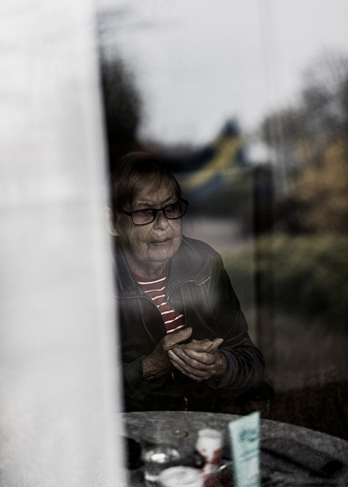 En äldre dam sitter vid sitt fönster
