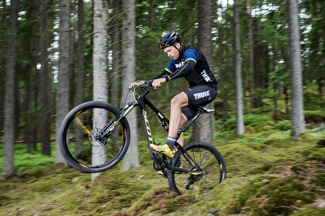 En ung man cyklar äventyrligt i skogen