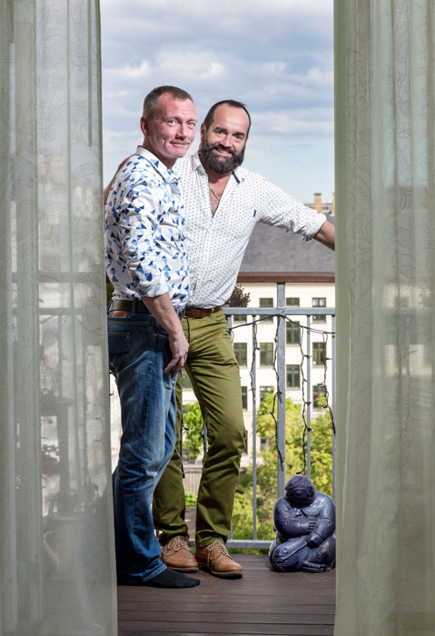 Två glada män står ute på en balkong