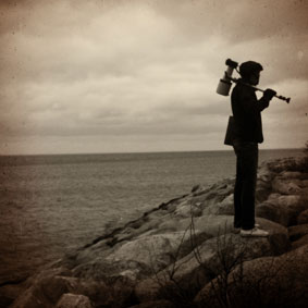 Fotografen André står med sin kamera över axeln vid havet