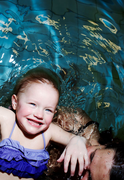 En leende flicka badar i en pool med en kvinna